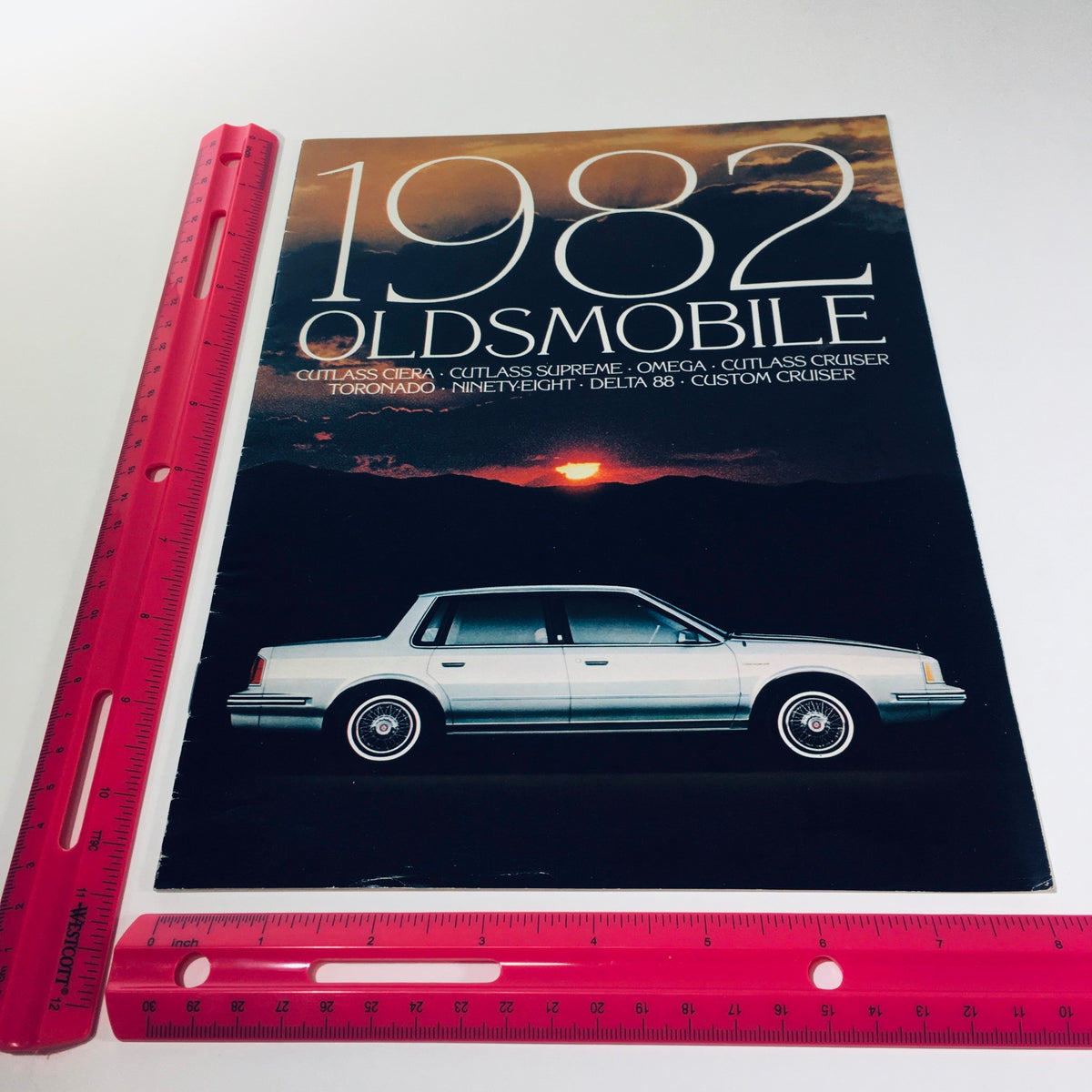 1982 Oldsmobile Cutlass Ciera, Supreme, Omega, Cruiser 9-81 Car Sales Brochure cover featuring the Oldsmobile logo and a detailed view of Oldsmobile models with a scenic background.