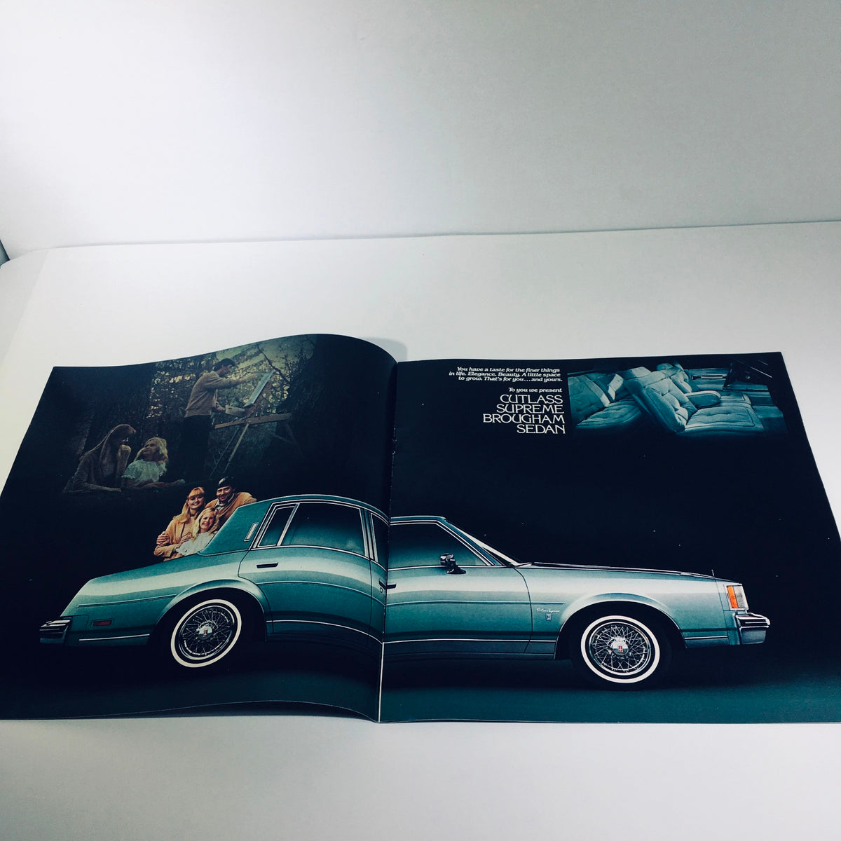 Opened view of the 1982 Oldsmobile Cutlass Supreme & Cutlass Cruiser sales brochure displaying the Cutlass Supreme Brougham Sedan alongside a family, reflecting on design and lifestyle.