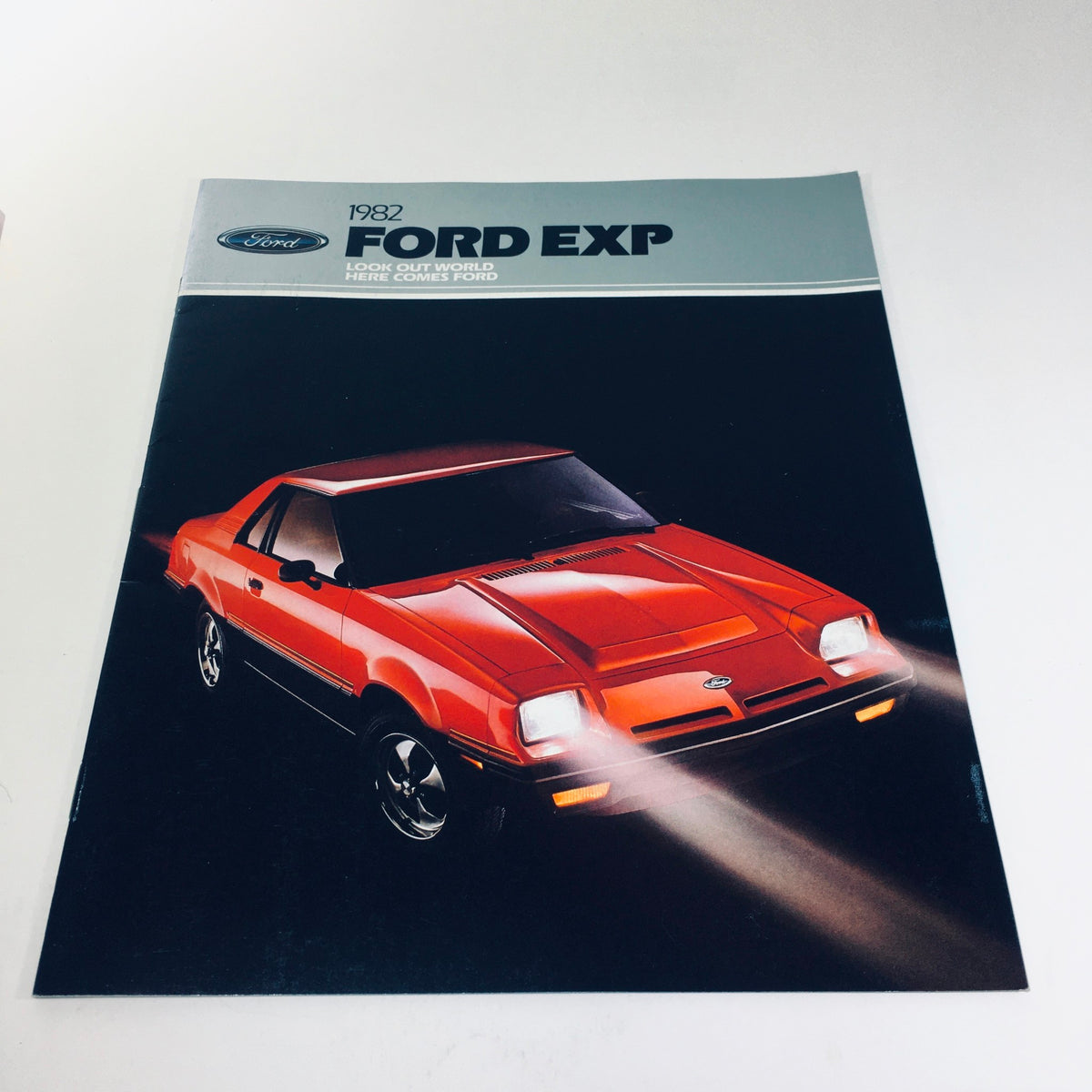 Cover of the 1982 Ford Exp Two-Seat Hatchback World-Class Coupe brochure featuring a red Ford EXP with headlights on.