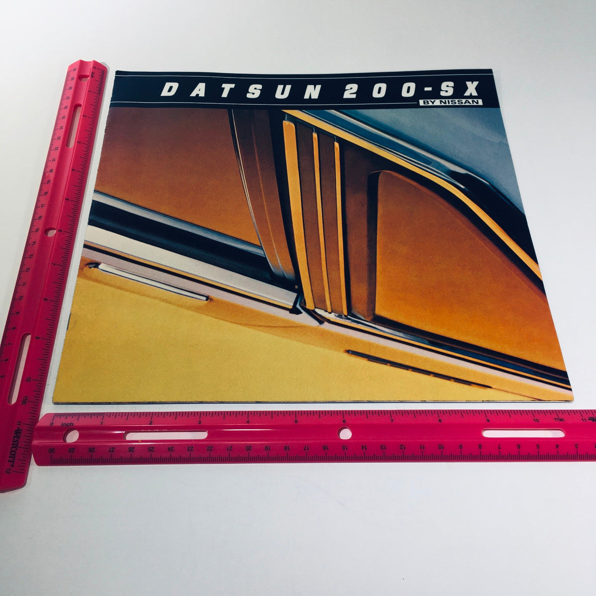 1981 Datsun 200-SX by Nissan Fuel Injected NAPS-Z Car Sale Brochure cover image focusing on the car's sleek lines and design details, incorporating a ruler for scale.