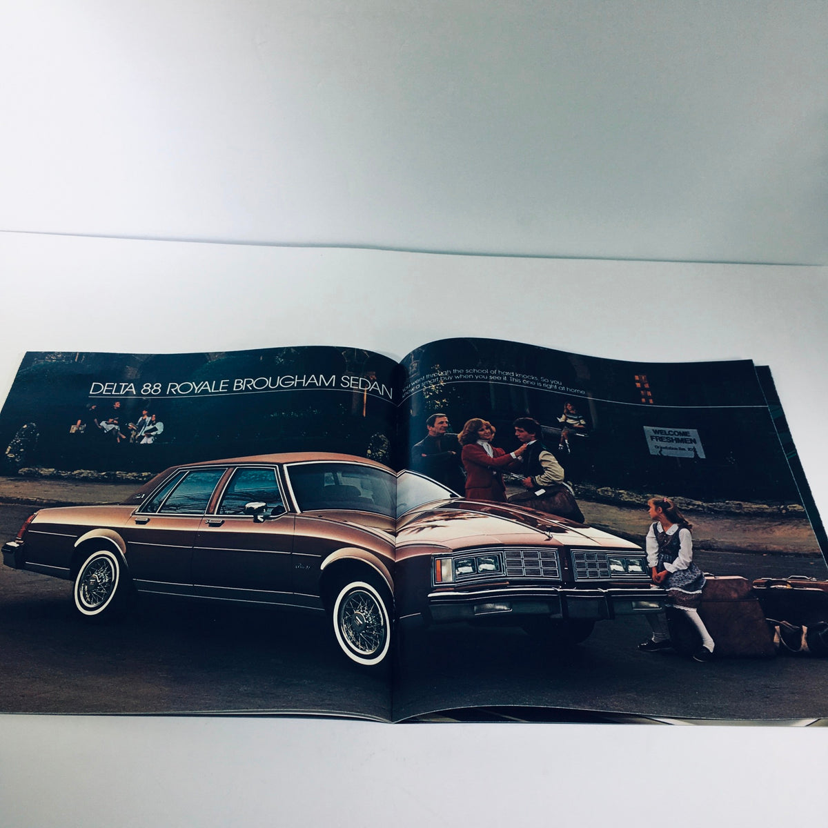 Page of the 1983 Oldsmobile Toronado Ninety-Eight Regency Delta 88 Custom Car Brochure featuring the Delta 88 Royale Brougham Sedan with a family setting.