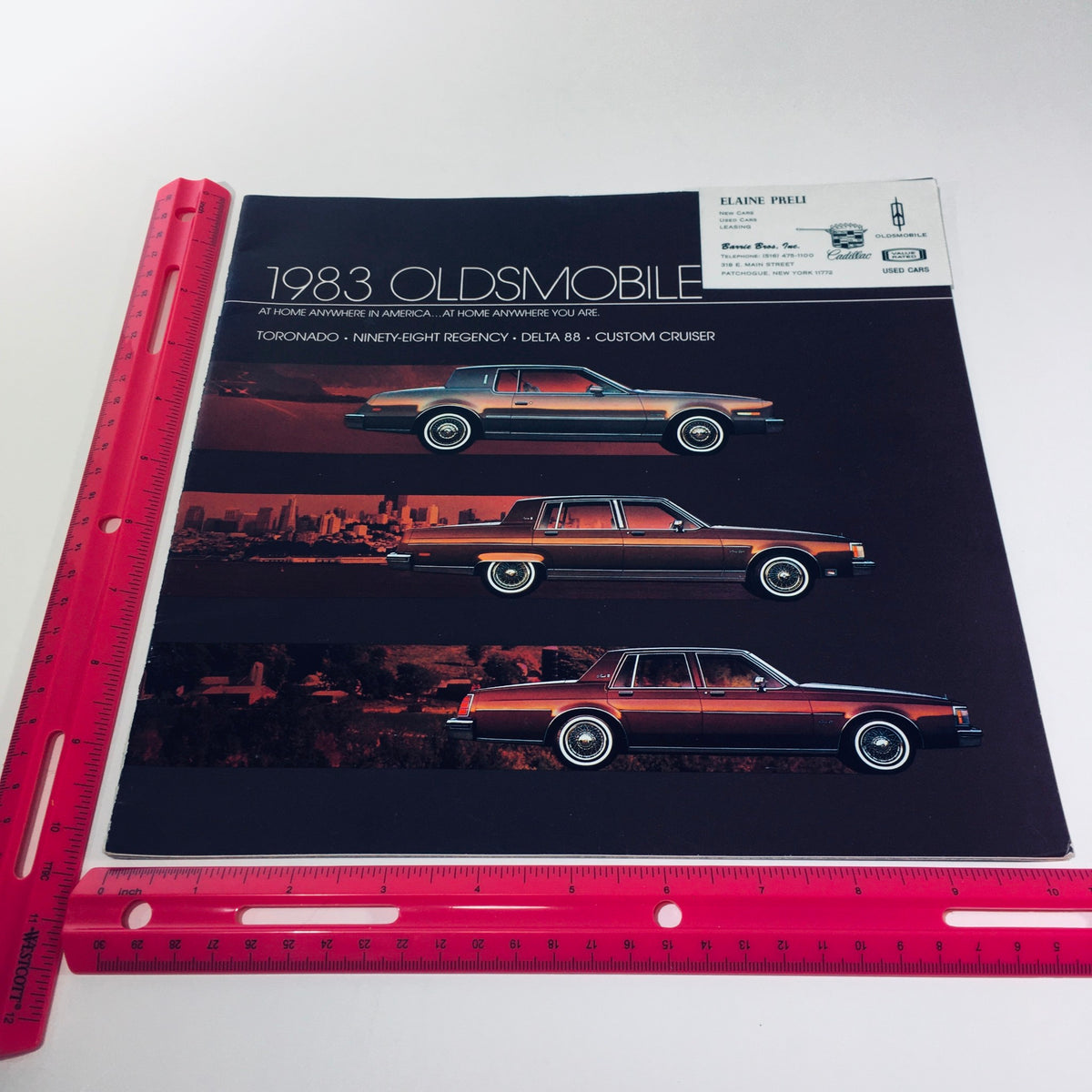 Front cover of the 1983 Oldsmobile Toronado Ninety-Eight Regency Delta 88 Custom Car Brochure, showcasing artistic images of the vehicles along with descriptive text and a ruler for size reference.
