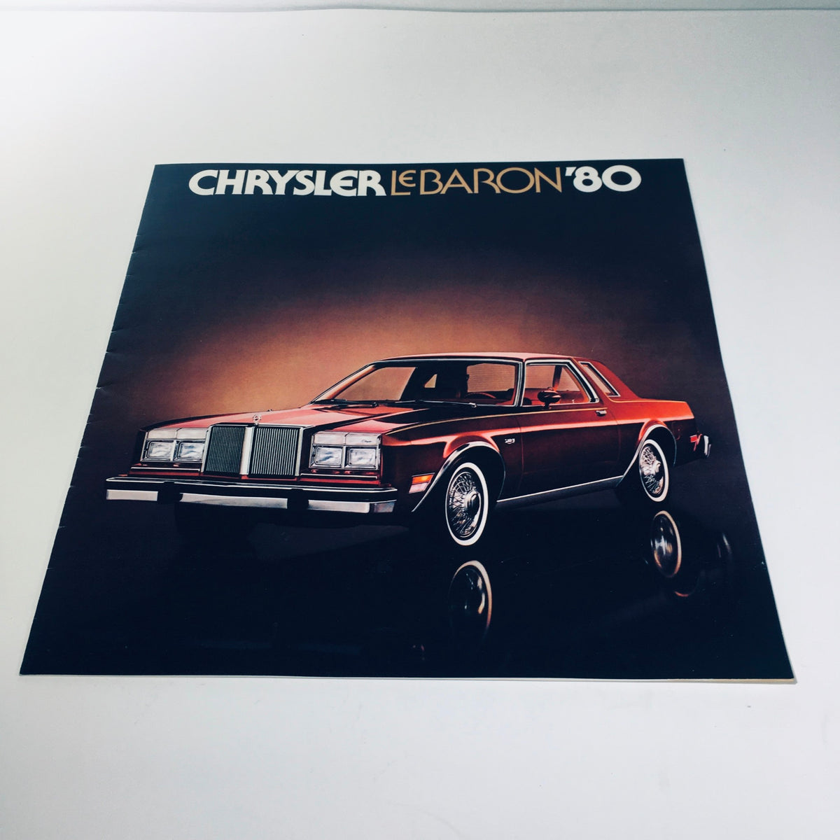 1980 Chrysler LeBaron Four-Door Medallion MOPAR Parts Car Sale Brochure Cover featuring a classic red Chrysler LeBaron with a stylish design against a dark background.