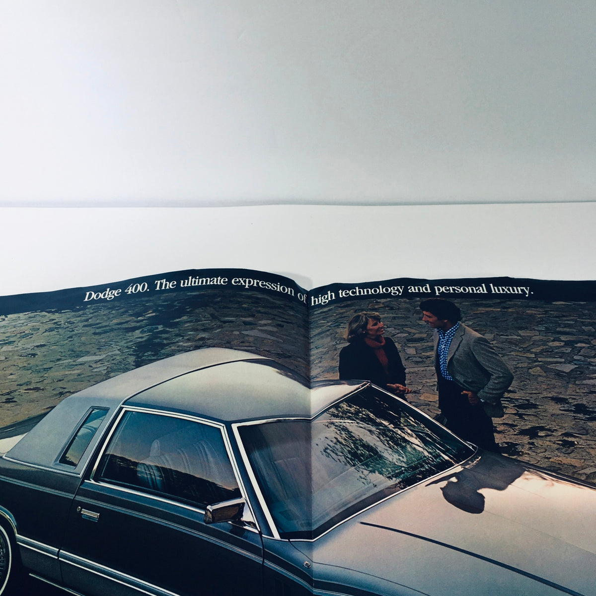 Detailed image of the 1982 Dodge 400 brochure with a focus on a couple examining the car, highlighting its luxurious appeal.