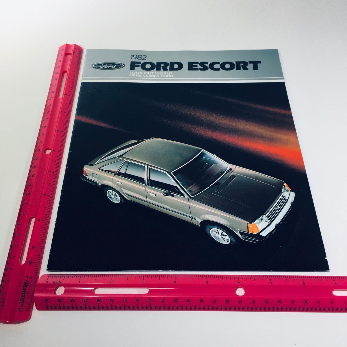 1982 Ford Escort brochure highlighting the sleek design of the 4-door hatchback, displayed alongside a ruler for size reference.