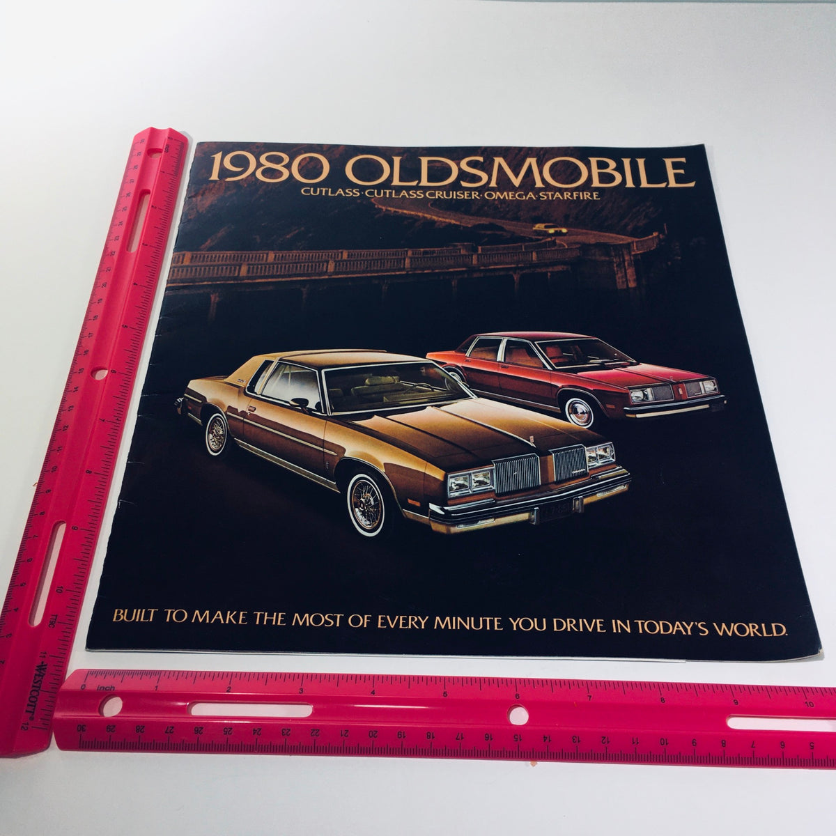 1980 Oldsmobile Cutlass, Cutlass Cruiser, Omega, Starfire V8 Power Car Brochure displayed with a ruler for size reference, showcasing the brochure's cover design and visuals.
