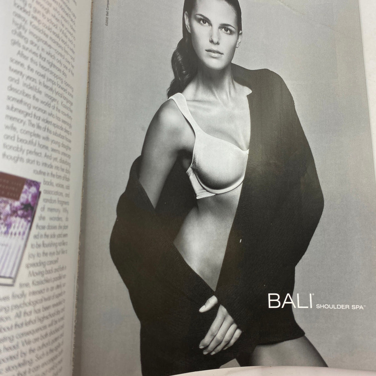 Advertisement from Elle Magazine March 2002 showcasing a model in a bra and oversized cardigan, emphasizing beauty and fashion in a black and white photo.