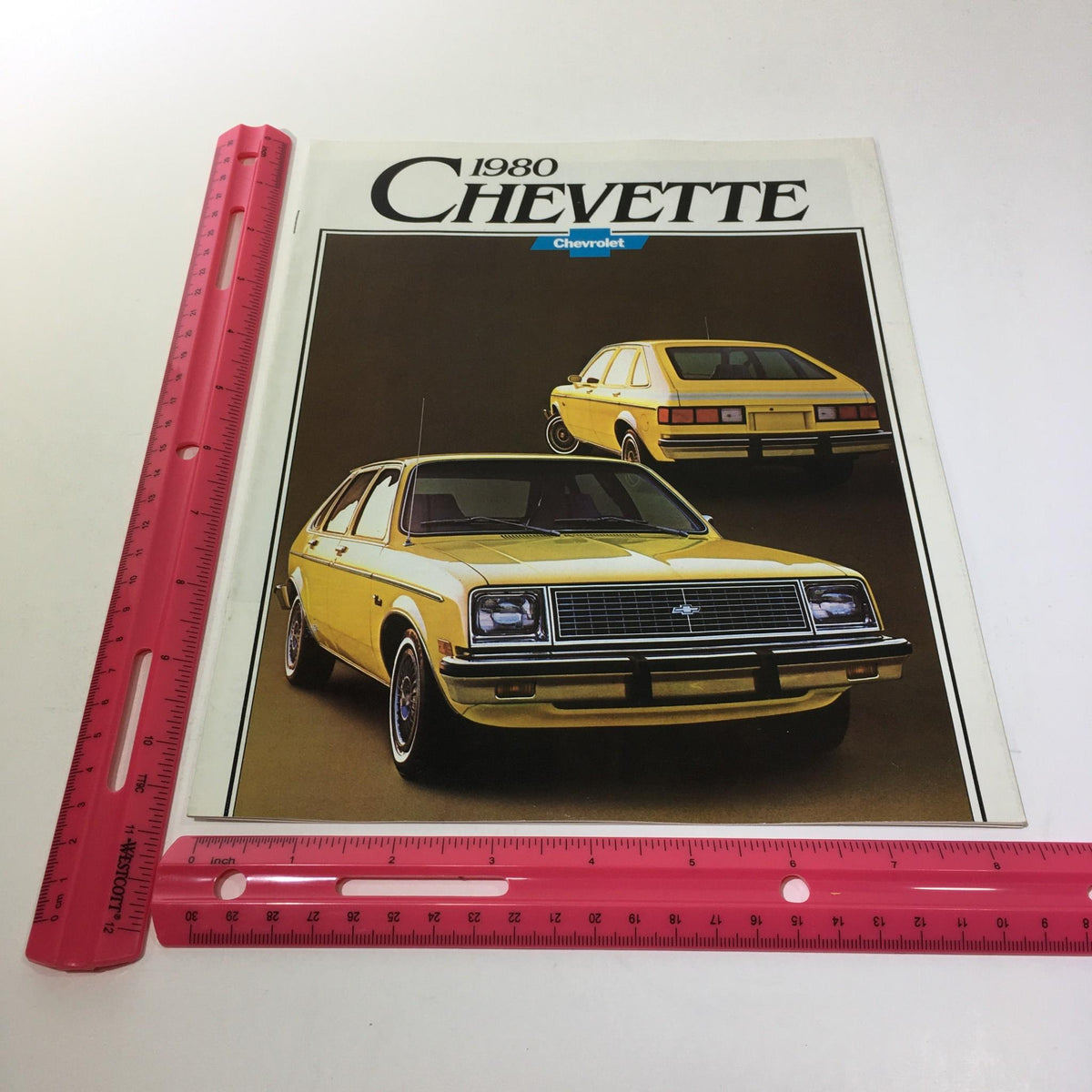 1980 Chevrolet Chevette brochure cover displayed with a ruler for size reference, showing the front and rear view of the yellow Chevette.