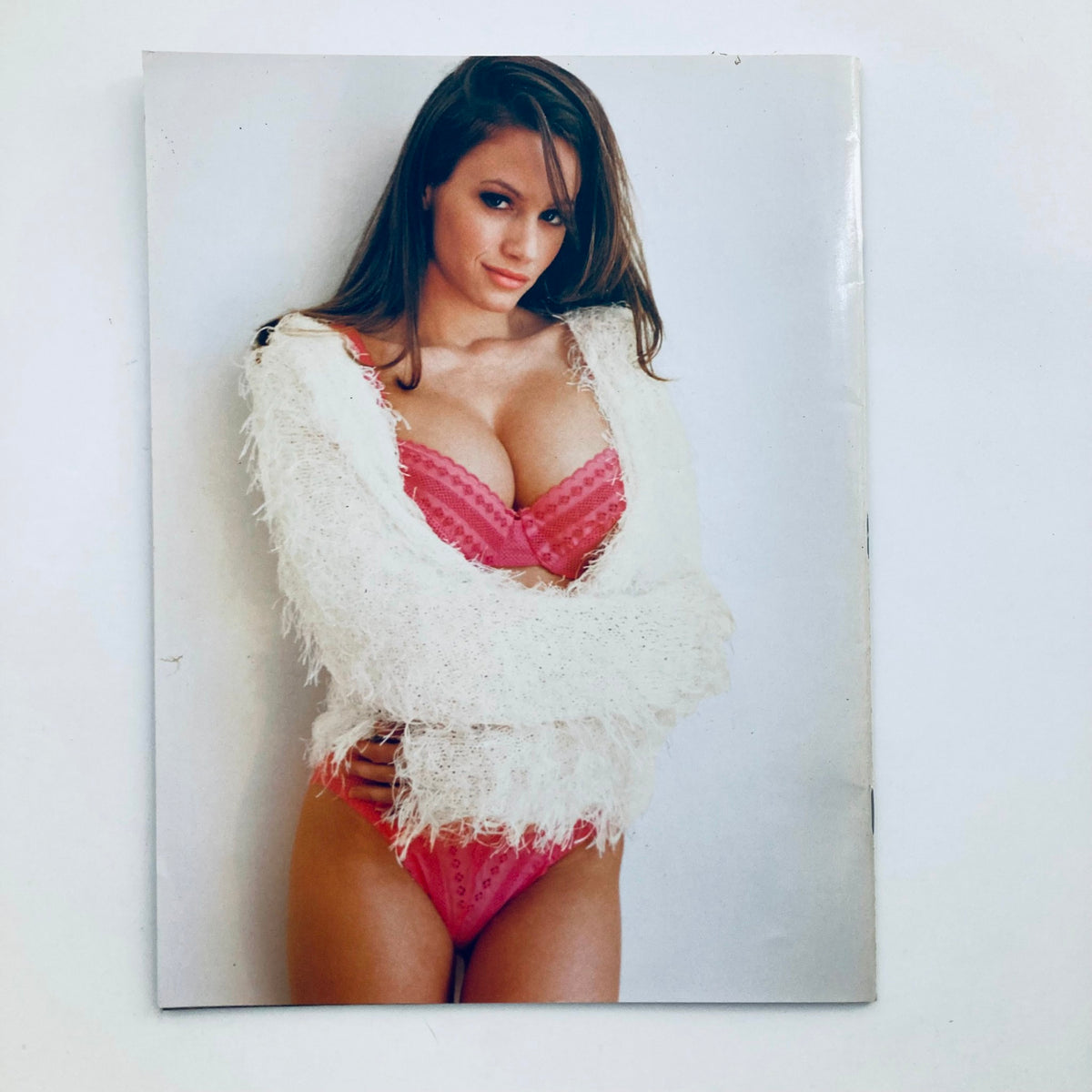 Playboy's Playmates Exposed Magazine 1998 showcasing a model with long dark hair in a pink lingerie set and a fluffy white sweater, presenting a confident pose.