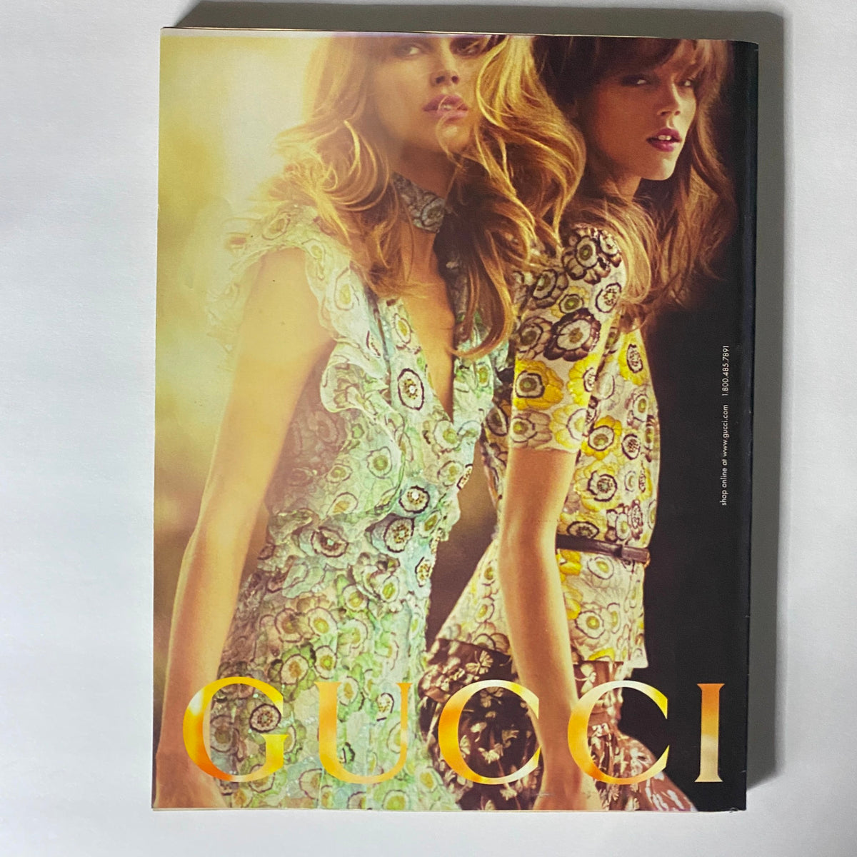 W Magazine April 2006 highlighting a vibrant Gucci advertisement with two models wearing colorful patterned dresses, reflecting high-fashion designs and the glamour of celebrity culture.