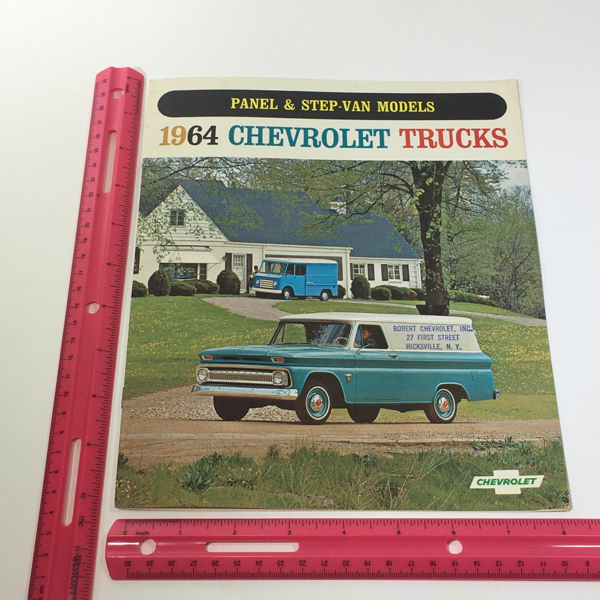 Close-up image of the cover of the 1964 Chevrolet Trucks Panel & StepVan Models Series P20 P30 Car Catalog Brochure, including a ruler for size reference.