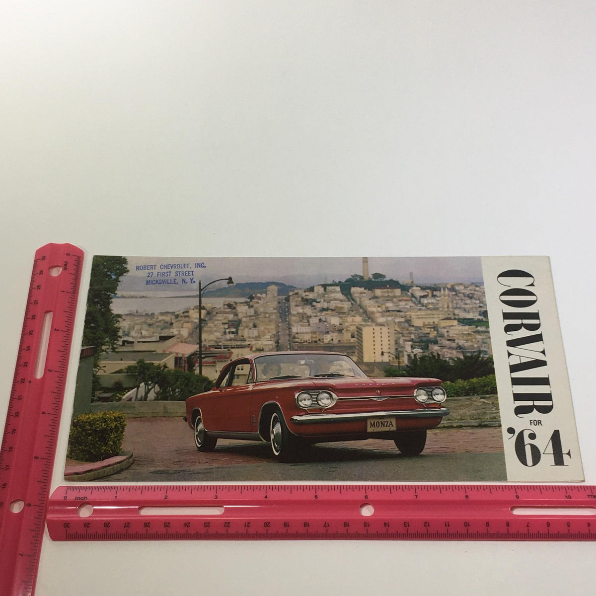 1964 Corvair by Chevrolet Turbo-Supercharged V-8 Engine 3-Speed Tran Car Catalog featuring a red Corvair Monza parked in a picturesque San Francisco setting with cityscape in the background.