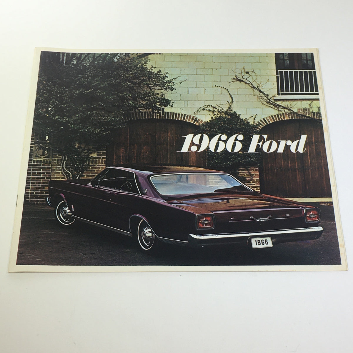 1966 Ford 200-HP V-8 Engine Cruise-O-Matic Drive Die-Cast Grill Car Catalog cover featuring a stylish maroon Ford car against a brick wall.