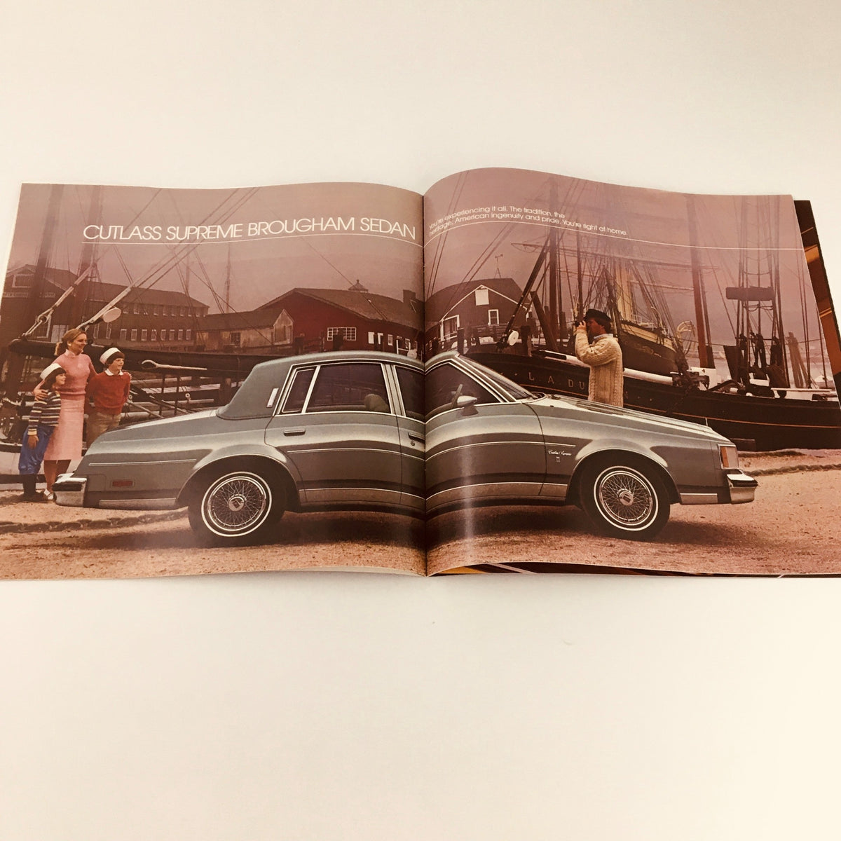 Image of a 1983 Oldsmobile Cutlass Supreme Brougham sedan featured in the brochure, set against a coastal backdrop.