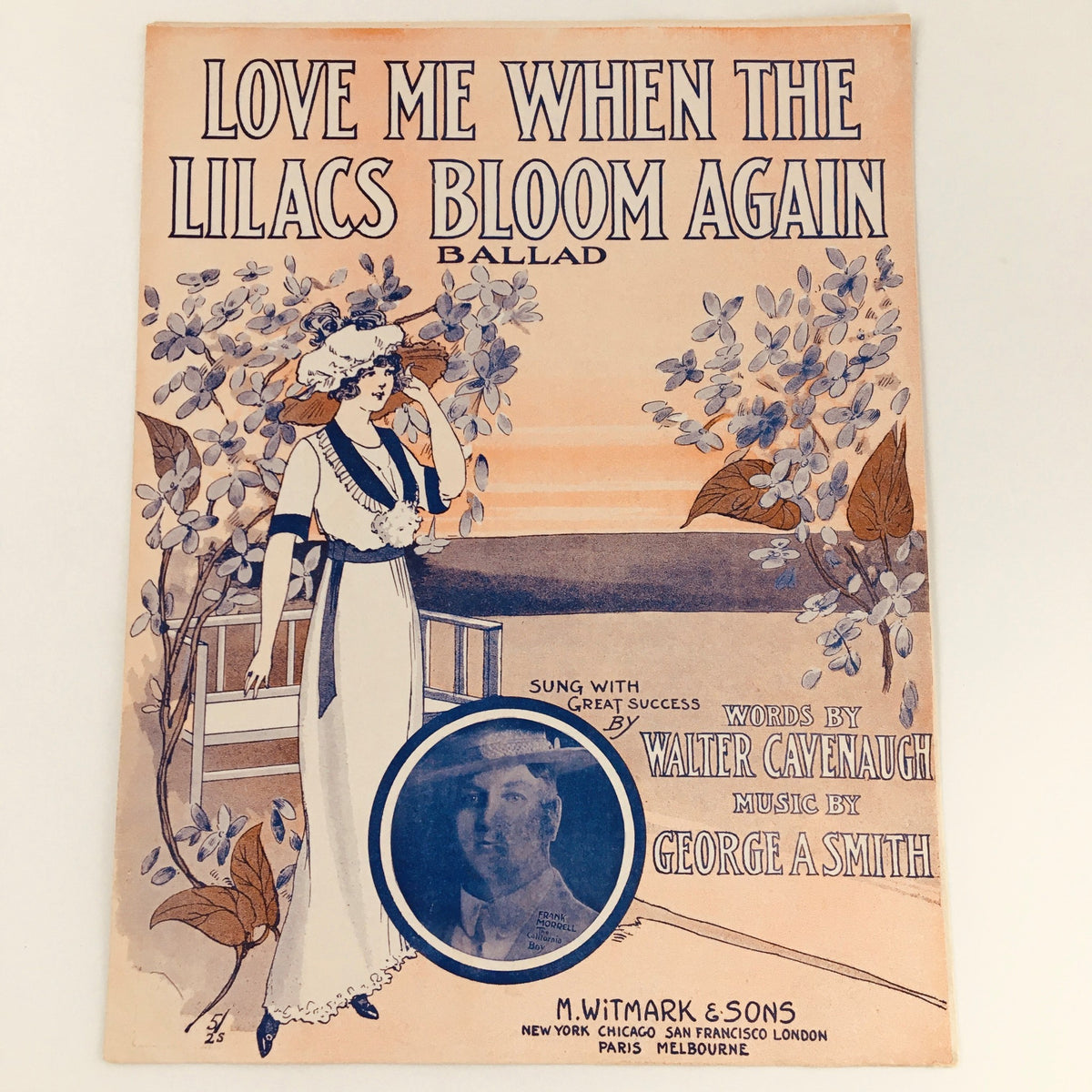 1912 Love Me When The Lilacs Bloom Again Ballad music sheet cover featuring elegant vintage illustration and musician details. Designed by Walter Cavenaugh with music by George A. Smith, showcasing classic early 20th-century aesthetics.