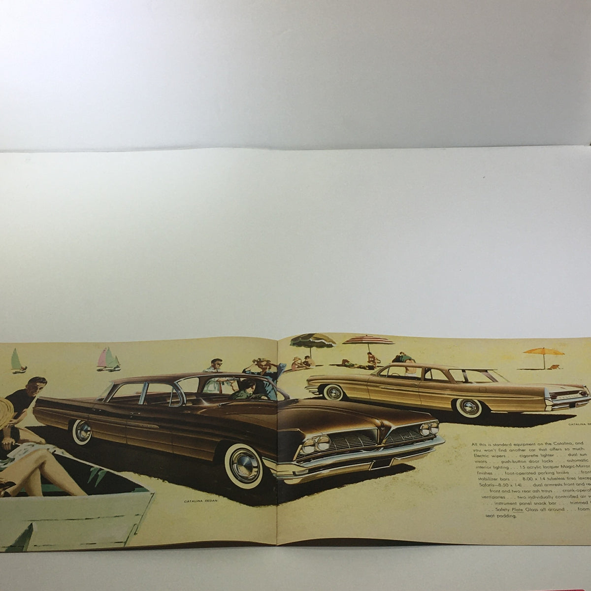 Inside view of the 1961 Pontiac Catalina 4-Door Sedan Safety Plate Glass Car Sale Brochure showing two cars on the beach surrounded by people.