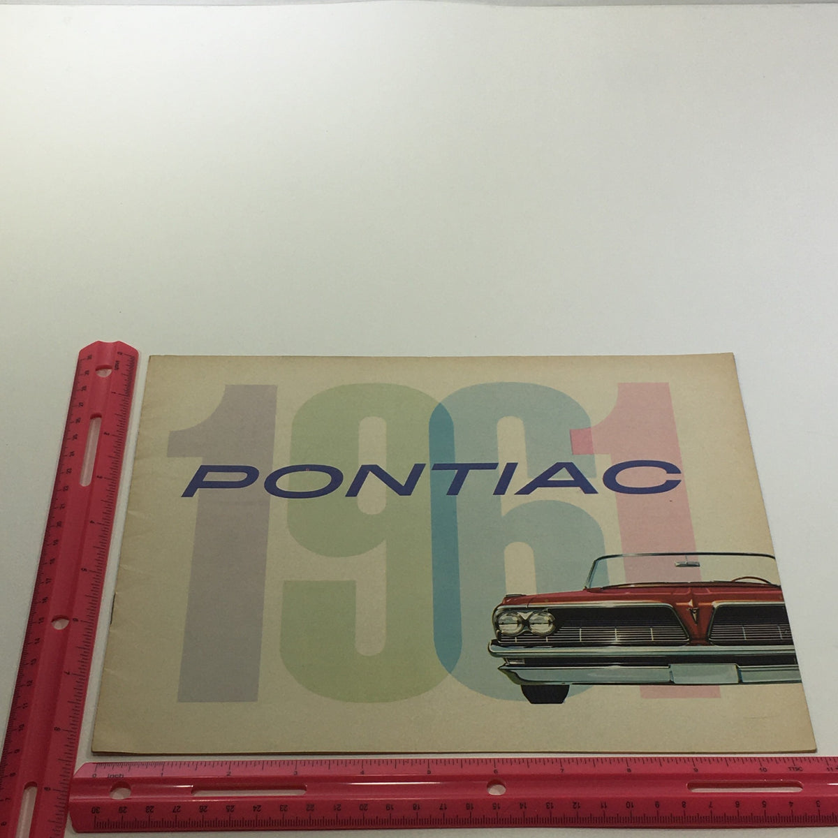 1961 Pontiac Catalina 4-Door Sedan Safety Plate Glass Car Sale Brochure displayed with a ruler for size reference.