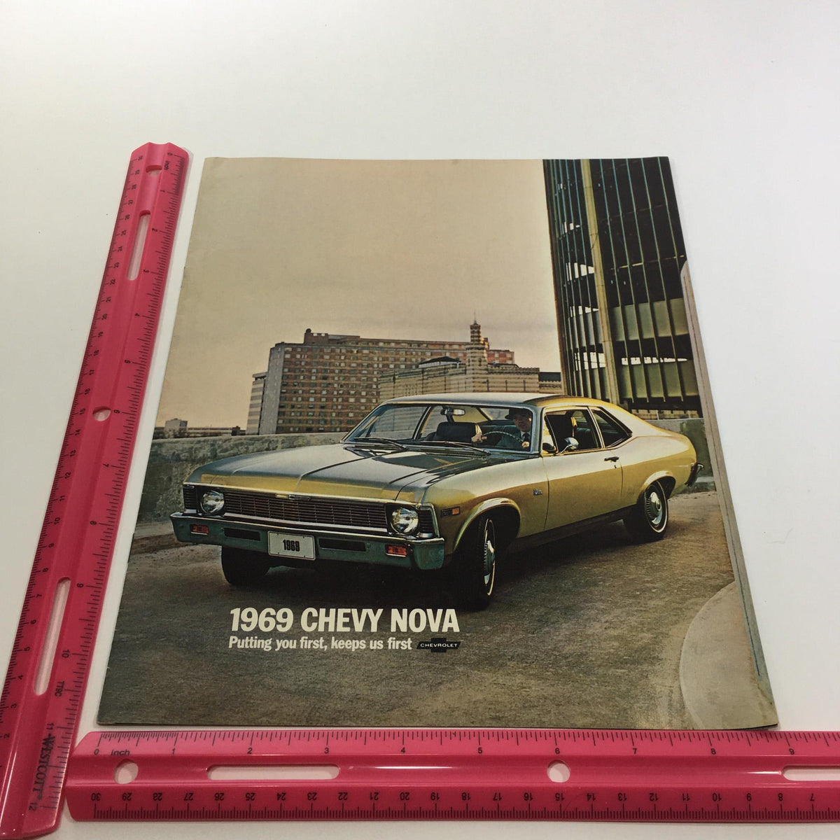 1969 Chevrolet Chevy Nova 2-Door Sedan SS Package Car Sale Brochure front cover with a ruler for size reference, highlighting its collectible vintage appeal.