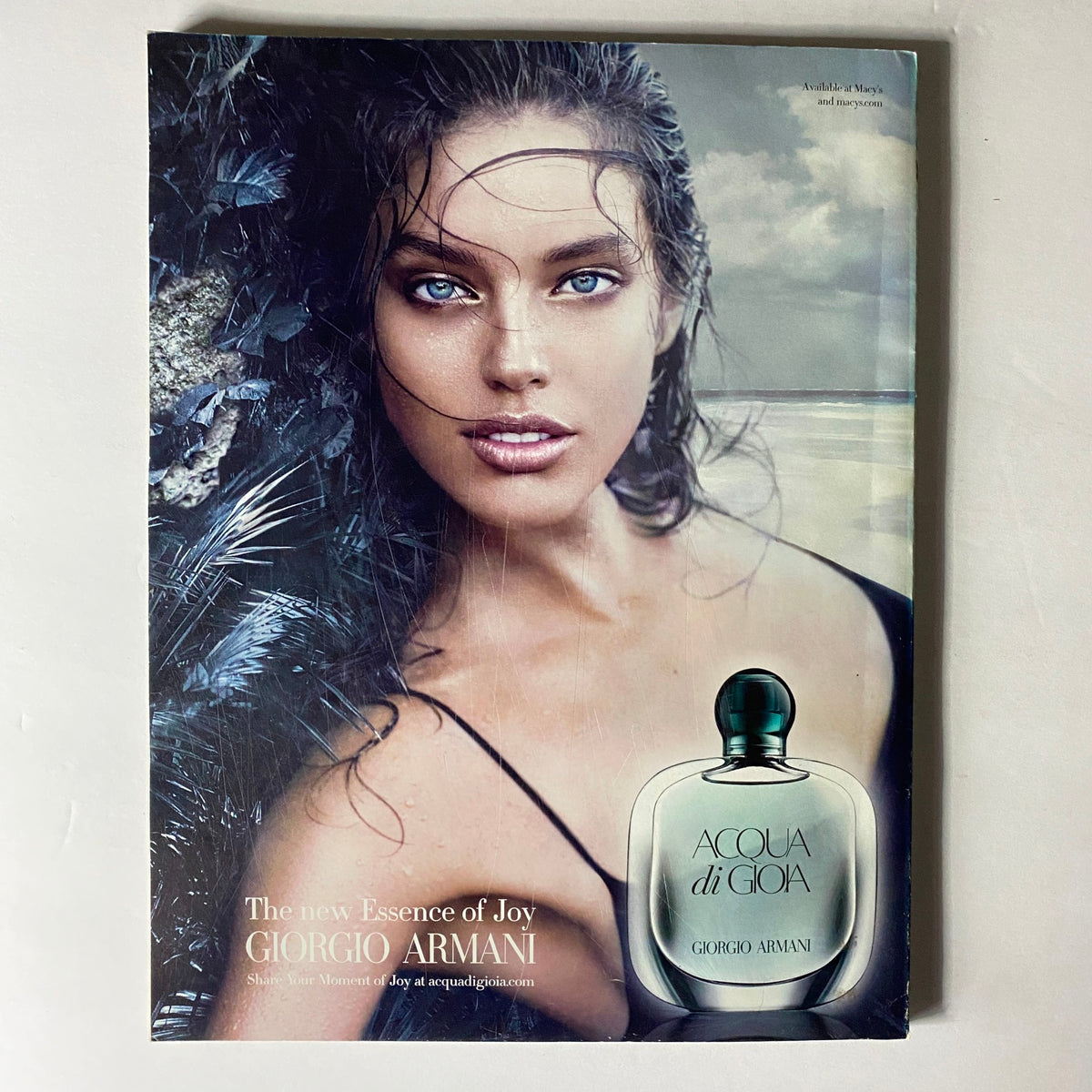 W Magazine December 2010 ad for Acqua di Gioia by Giorgio Armani, highlighting a beautiful model with striking blue eyes against a scenic backdrop, emphasizing beauty and elegance.
