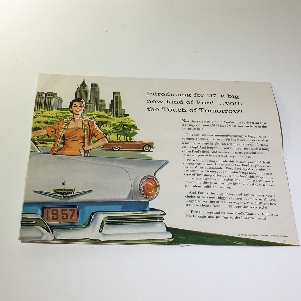 1957 Ford Touch of Tomorrow Master-Guide Power Steering Car Catalog Brochure introducing the new Ford for '57, featuring a woman standing by a car with a city skyline in the background, highlighting the stylish design and features.