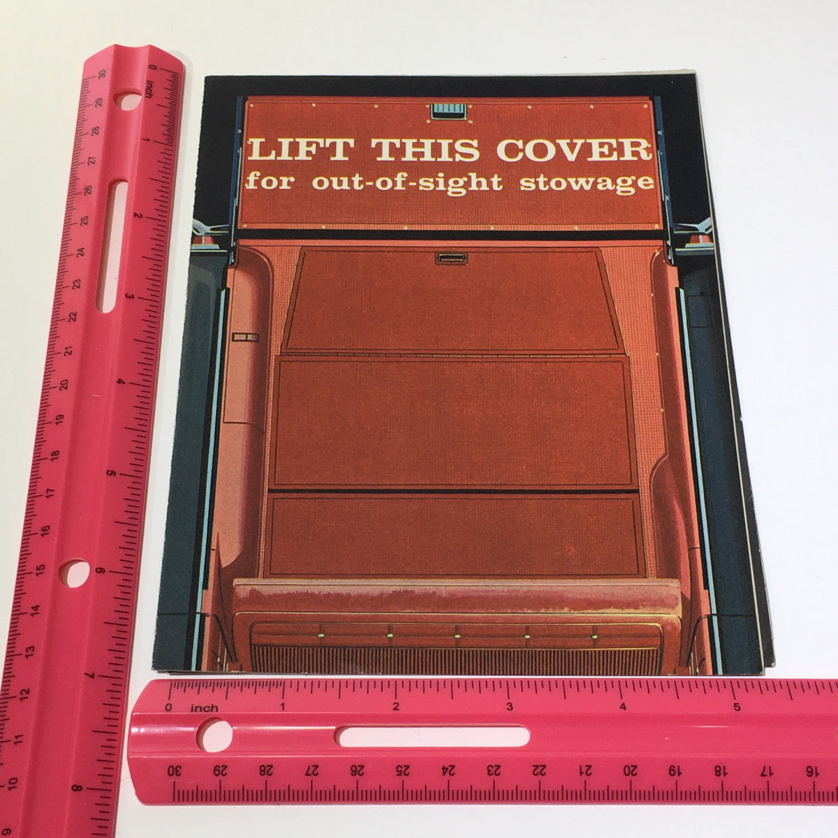 Cover page of the 1962 Chevrolet Wagons Impala 6-Passenger Wagon Greenbrier De Luxe Sports Catalog, featuring a vibrant design with the text 'LIFT THIS COVER for out-of-sight stowage' and a ruler for scale.