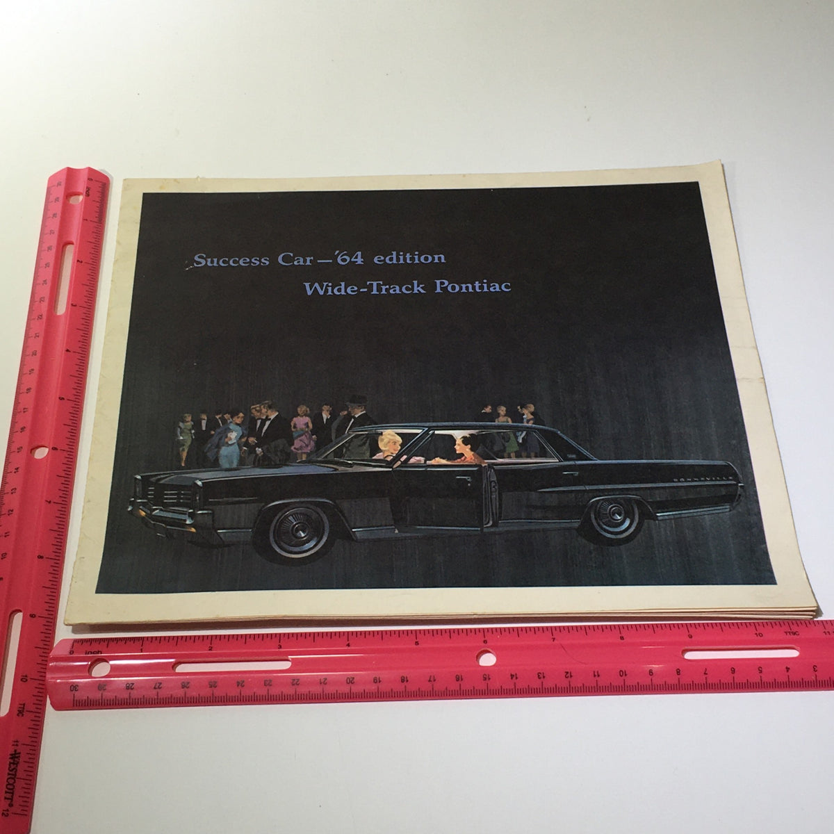 View of the cover of the 1964 Success Car Edition: Wide-Track Pontiac Trophy V-8 E Car Catalog Brochure alongside a ruler for size reference.