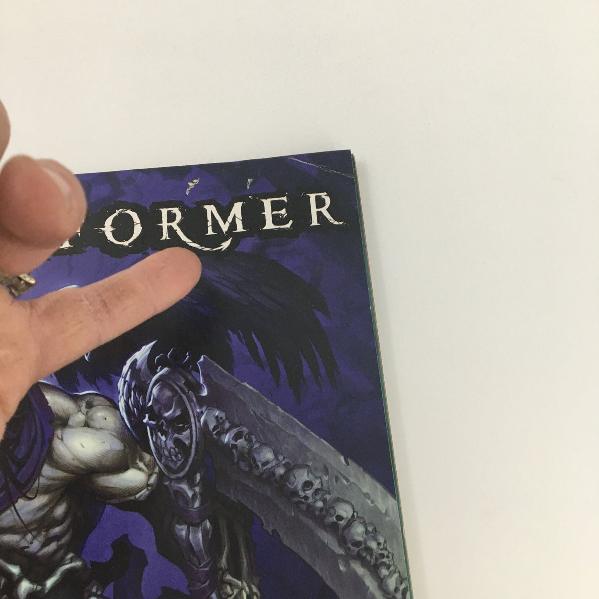 Detail of the cover of Game Informer Magazine July 2011 Issue 219, highlighting the title 'Game Informer' and artistic elements, with a hand partially covering the top corner.