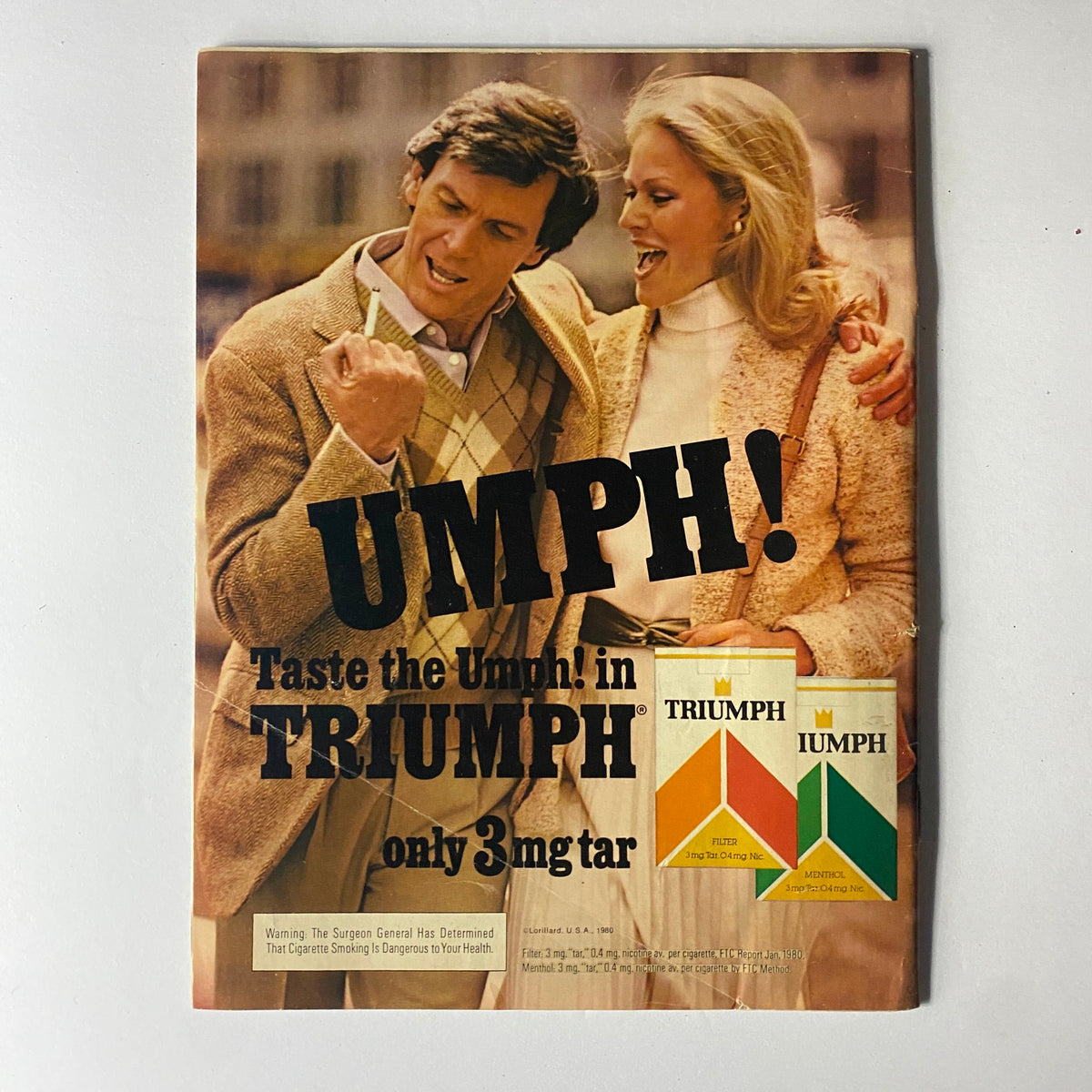 Vintage advertisement with the title 'UMPH!' for Triumph cigarettes, showcasing a man and woman in stylish 1980s attire, with the phrase 'Taste the Umph! in Triumph' prominently displayed.
