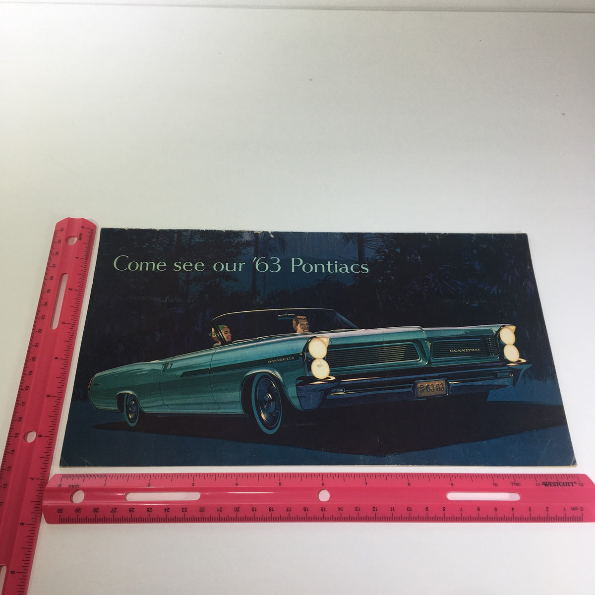 1963 Pontiacs' The Bonnevilles Convertible 2-Door Sedan Car Catalog Brochure featuring a classic turquoise Pontiac with a picturesque background, showcasing vintage automotive design.