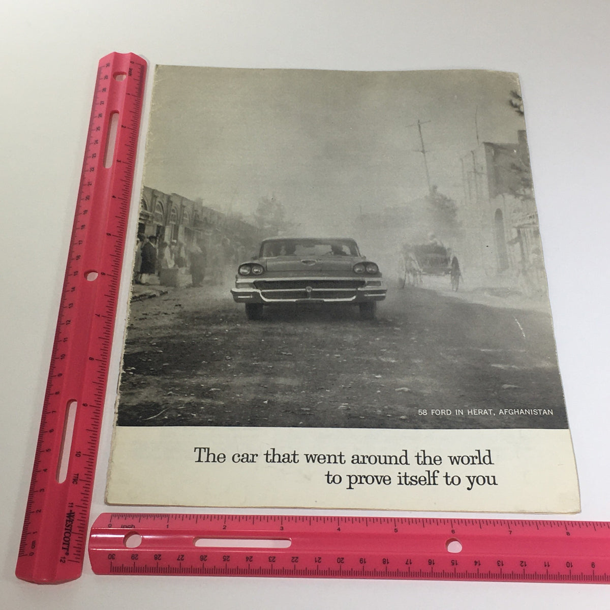 1958 Ford 2-Door Sedan Hardtop Russian Frontier Car Catalog Brochure cover displaying a car in Herat, Afghanistan, with the tagline 'The car that went around the world to prove itself to you'.