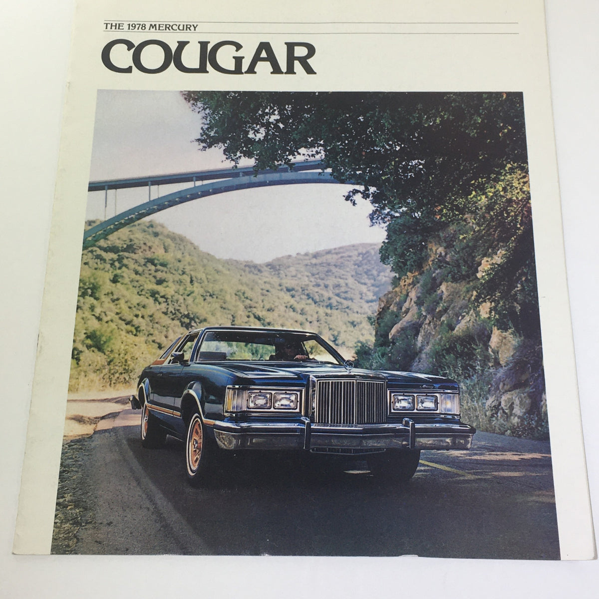 Cover of the Vintage 1978 Mercury Cougar XR-7 catalog featuring a sleek blue car parked on a scenic road with mountains in the background.