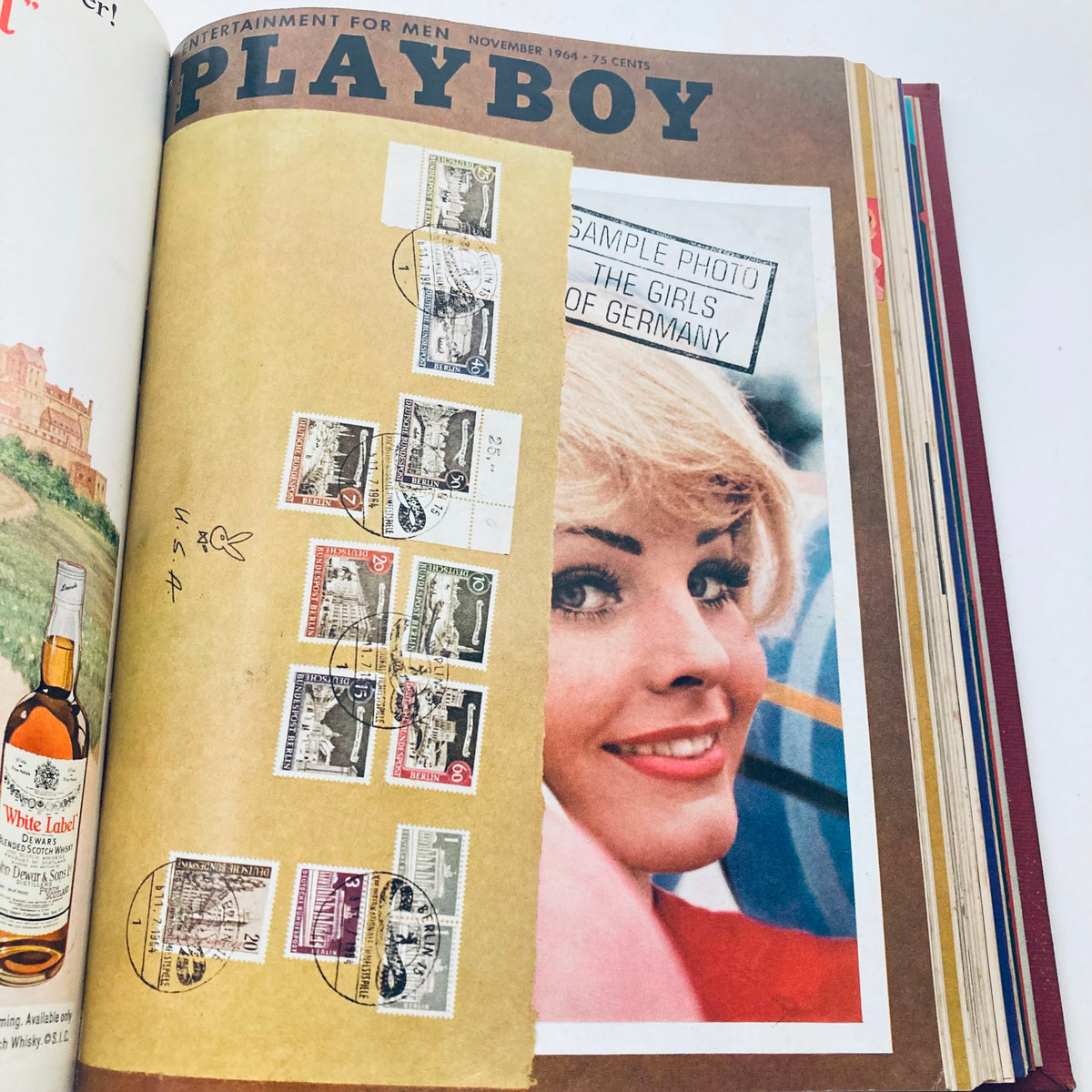 Cover page of the Complete 1964 Original Playboy Magazine, November issue displaying vintage stamp collection and a beautiful woman, encapsulating cultural moments of the year.