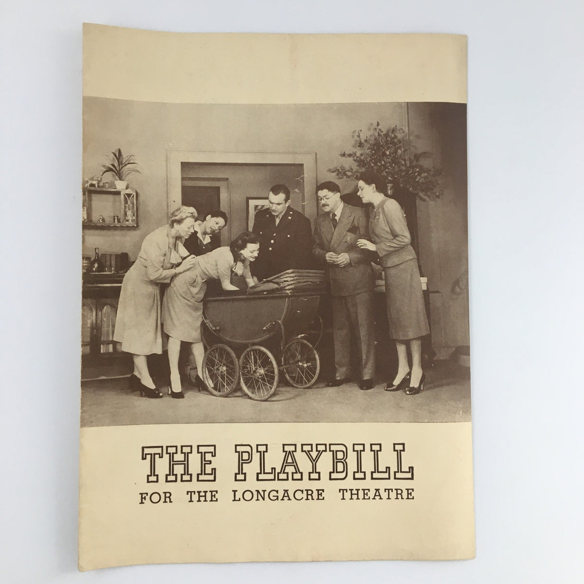 1943 Playbill for 'Three's A Family' at the Longacre Theatre, showcasing a scene with actors around a baby carriage in a vintage setting.