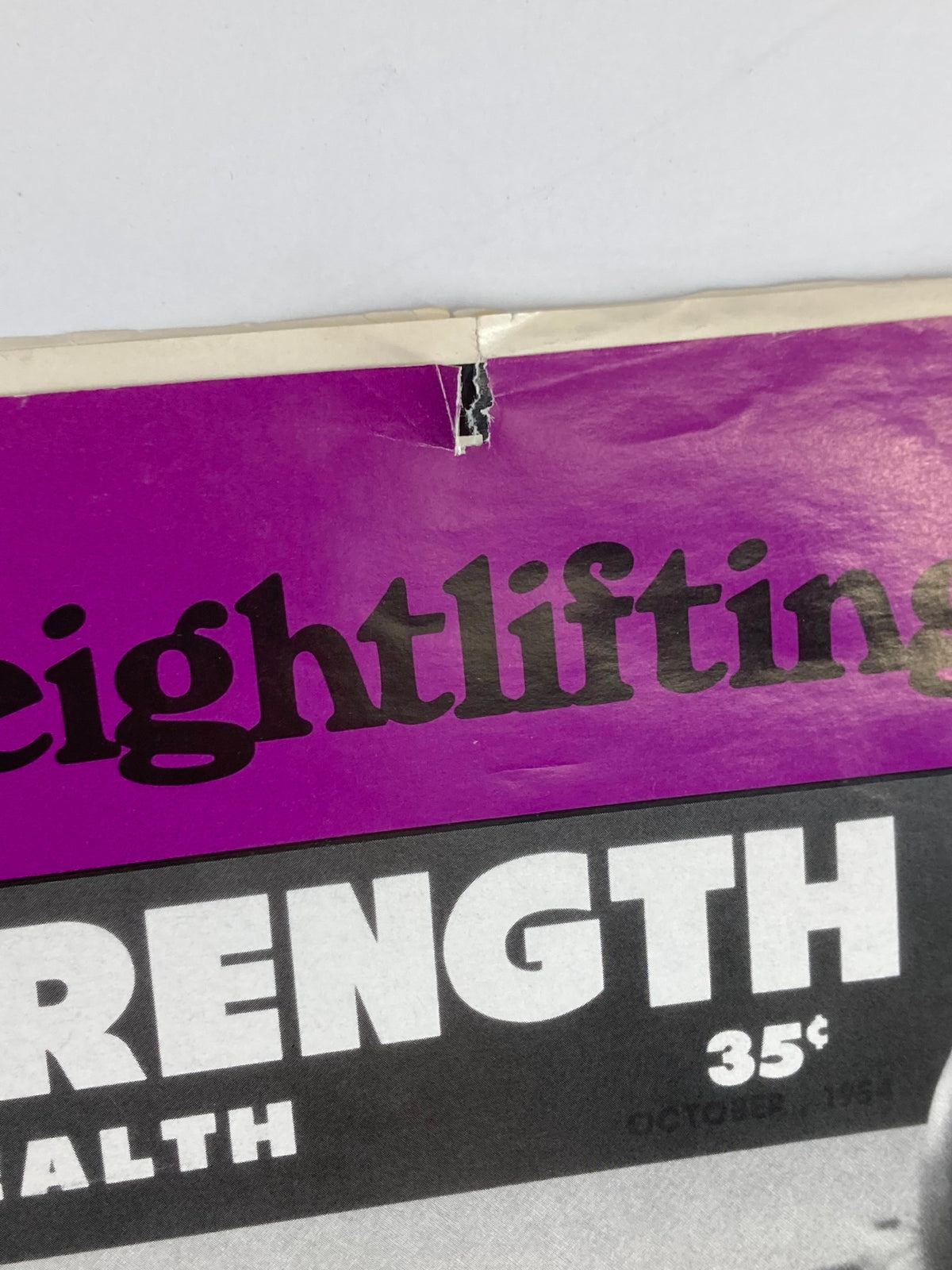 Detail shot of damage on the Weightlifting USA Magazine cover, highlighting the title and date, January 1988, Vol 6 #1.
