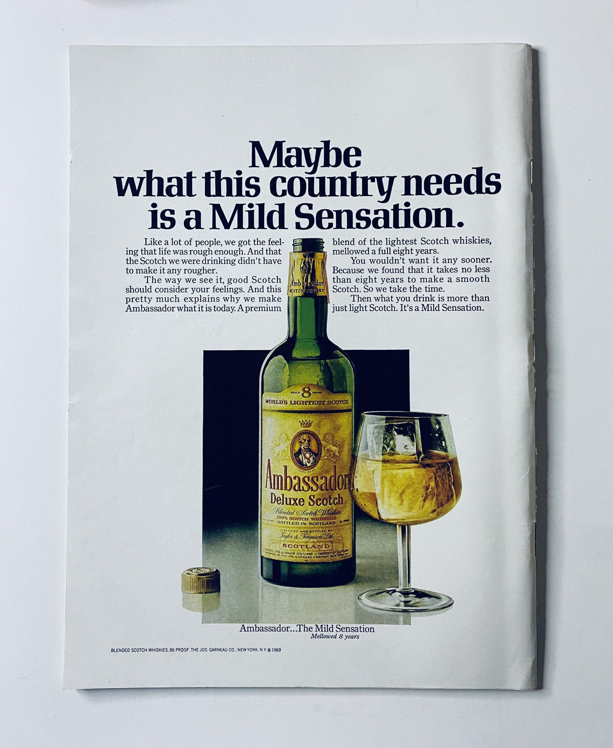 Advertisement in The New Yorker Magazine August 16, 1969 for Ambassador Deluxe Scotch, depicting a bottle and a glass of scotch, emphasizing the phrase 'Maybe what this country needs is a Mild Sensation'.