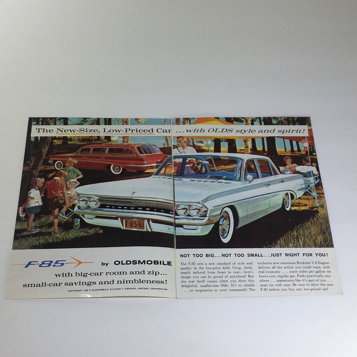 Inside view of the Vintage 1961 All New F-85 Oldsmobile brochure showing a white Oldsmobile with families enjoying the spacious interior, promoting the car's savings and spirit.