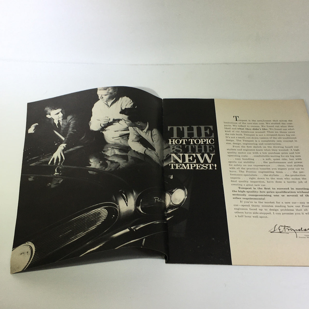 Inside page of the Vintage Pontiac Tempest catalog highlighting the slogan 'THE HOT TOPIC IS THE NEW TEMPEST!' with a photograph of men discussing the car.