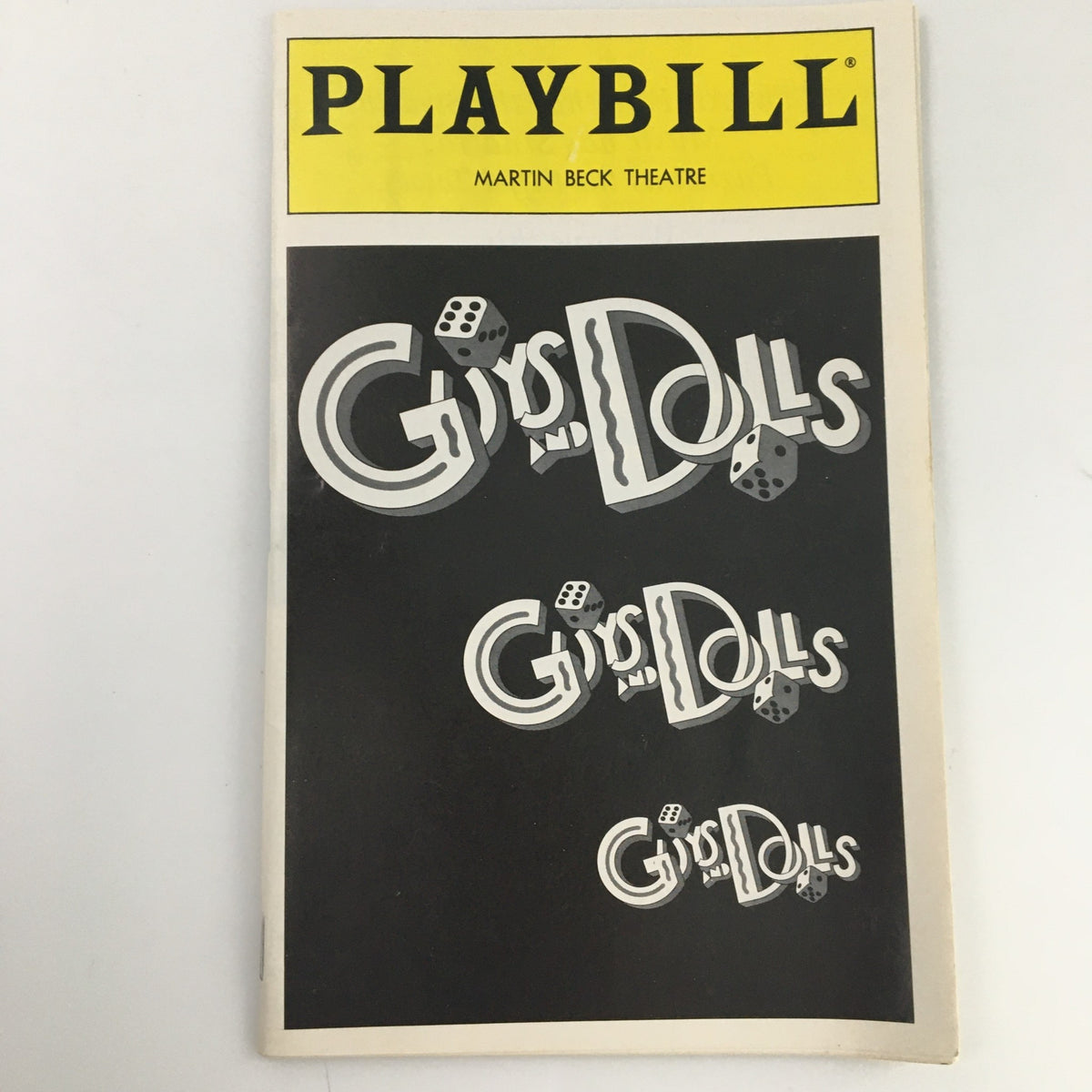 Detailed view of the 1994 Playbill for Guys and Dolls at Martin Beck Theatre, highlighting the cover design with repeated title display and dice imagery.