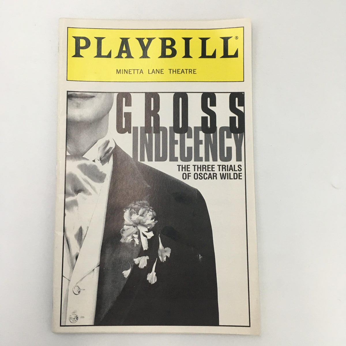 Cover of the 1997 Playbill for 'Gross Indecency' at Minetta Lane Theatre, showcasing a black and white image of a man in formal attire with a flower, directed by Moises Kaufman.