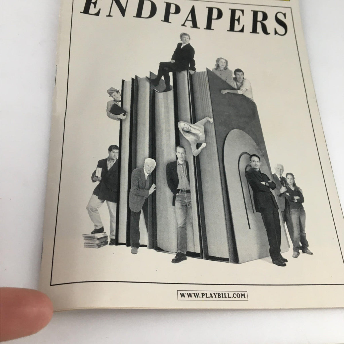 2002 Playbill Endpapers by Variety Arts Theatre featuring a group of theater performers on oversized books, capturing the essence of theatrical creativity.