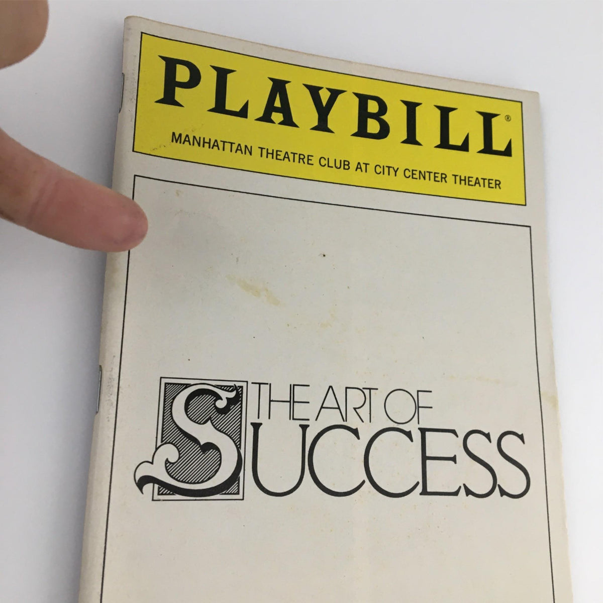 Close-up view of the 1990 Playbill for The Art of Success by Manhattan Theatre Club, highlighting the cover details and slight wear.
