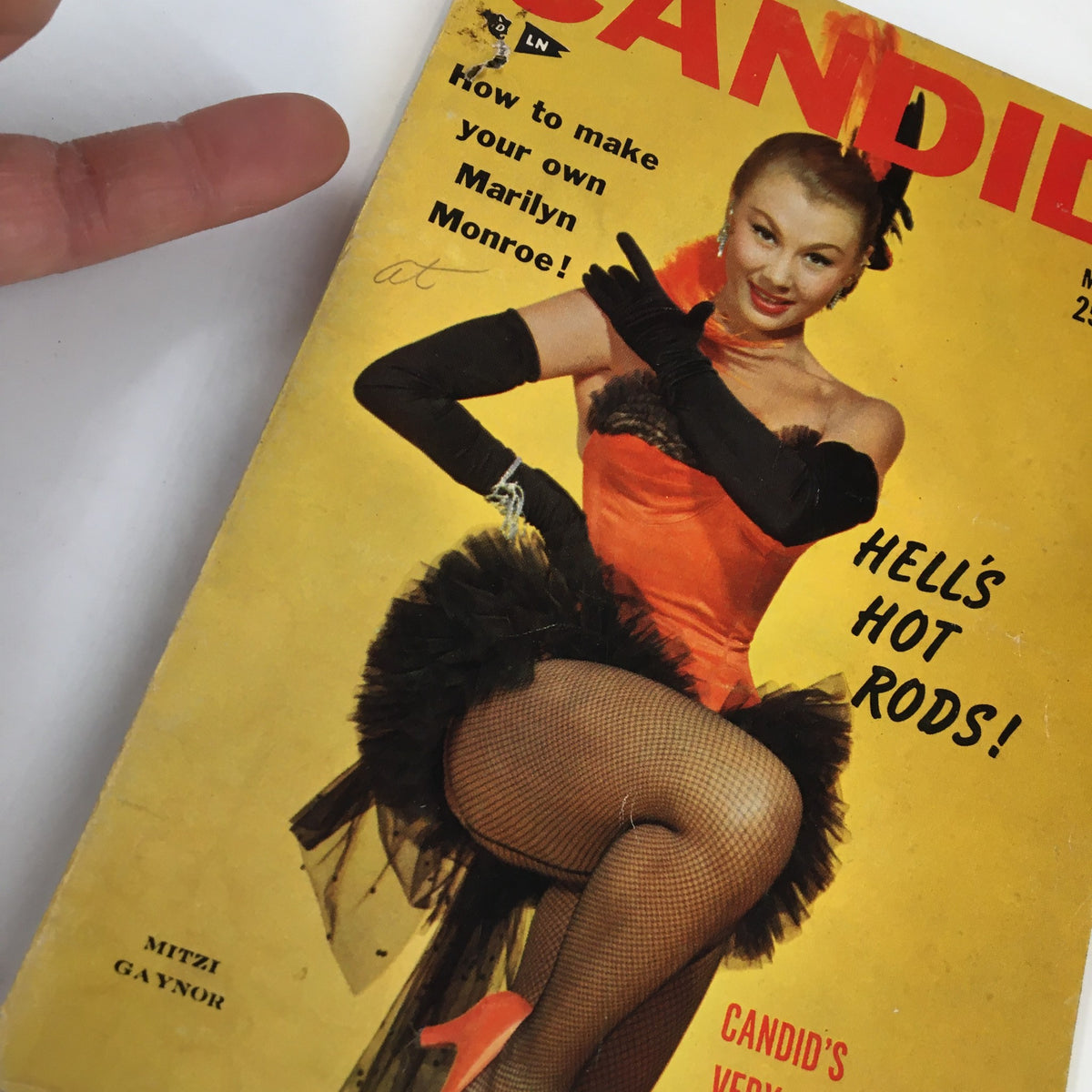 Close-up of VTG Candid Magazine May 1954 cover featuring Mitzi Gaynor, showcasing her glamorous outfit and playful expression, a classic representation of 1950s entertainment culture.