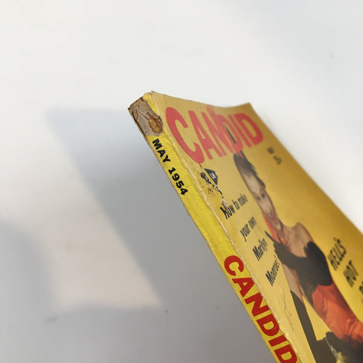 Side view of VTG Candid Magazine May 1954 showing wear on the cover, highlighting its vintage charm and authenticity.