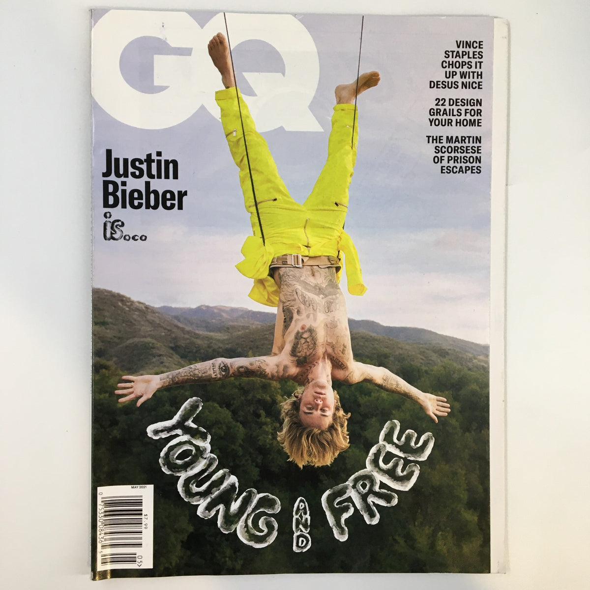 GQ Magazine May 2021 cover featuring Justin Bieber in a vibrant yellow outfit, hanging upside down with the title 'Young and Free No Label' prominently displayed.