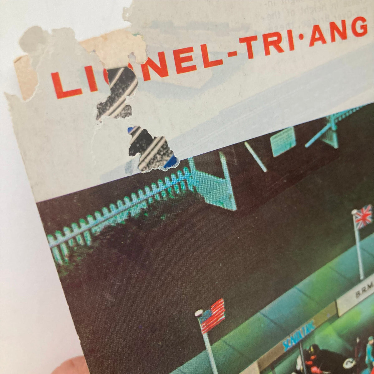 Damaged corner of the 1962 Lionel Trains and Accessories Model Motor Racing Catalog cover, revealing age and wear while still showcasing branding details.