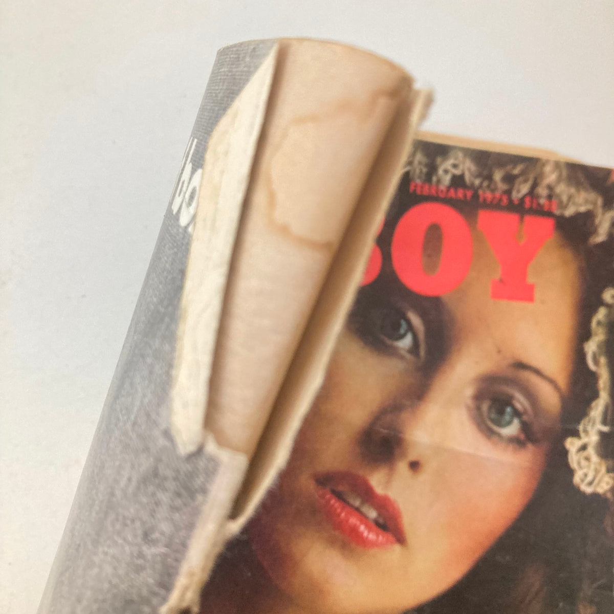Side view of VTG Playboy Magazine February 1975, highlighting the spine and wear of the magazine, emphasizing its vintage character.