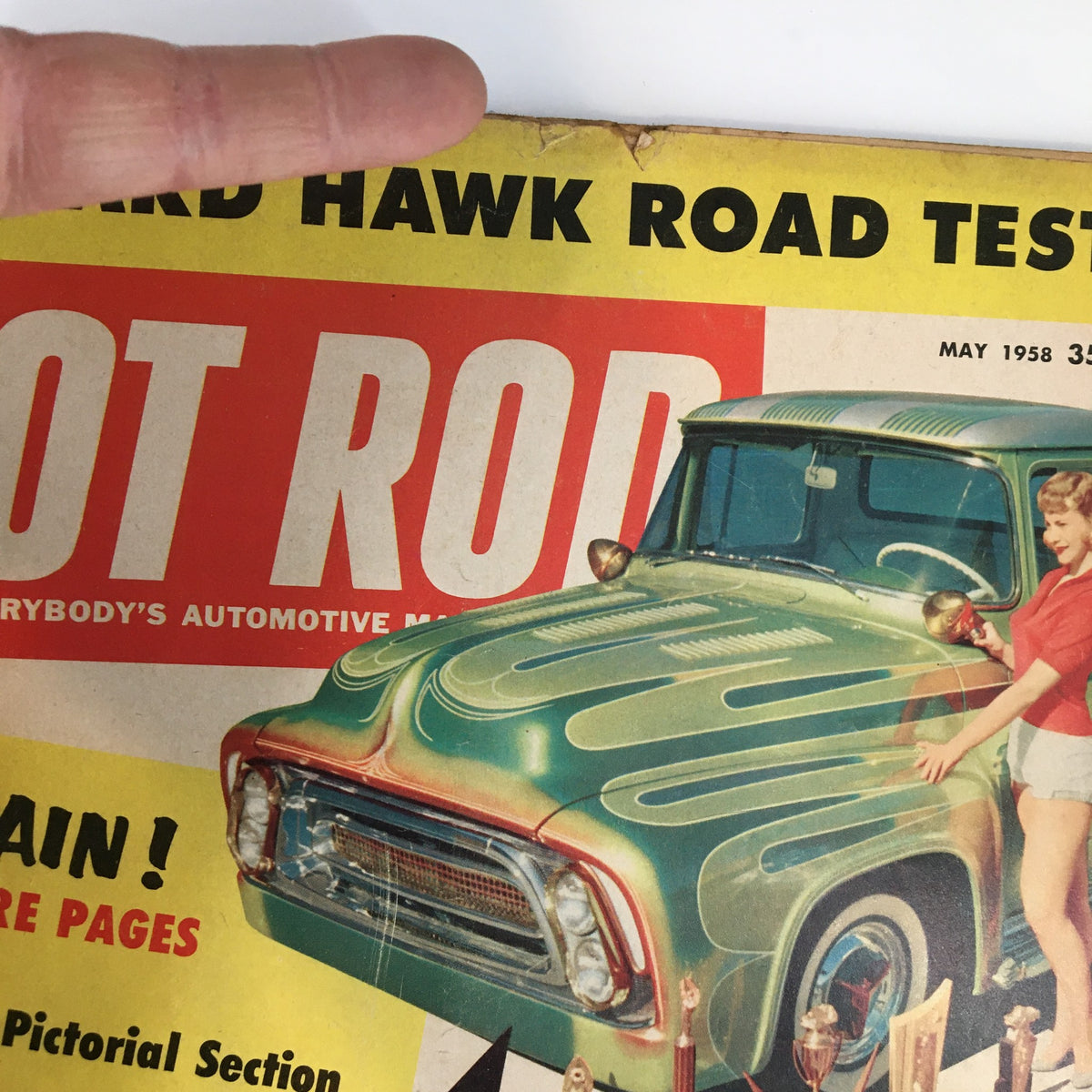 Detailed view of the May 1958 Hot Rod Magazine cover showcasing a woman interacting with a green hot rod truck and emphasizing the retro design popular in 1950s automotive magazines.