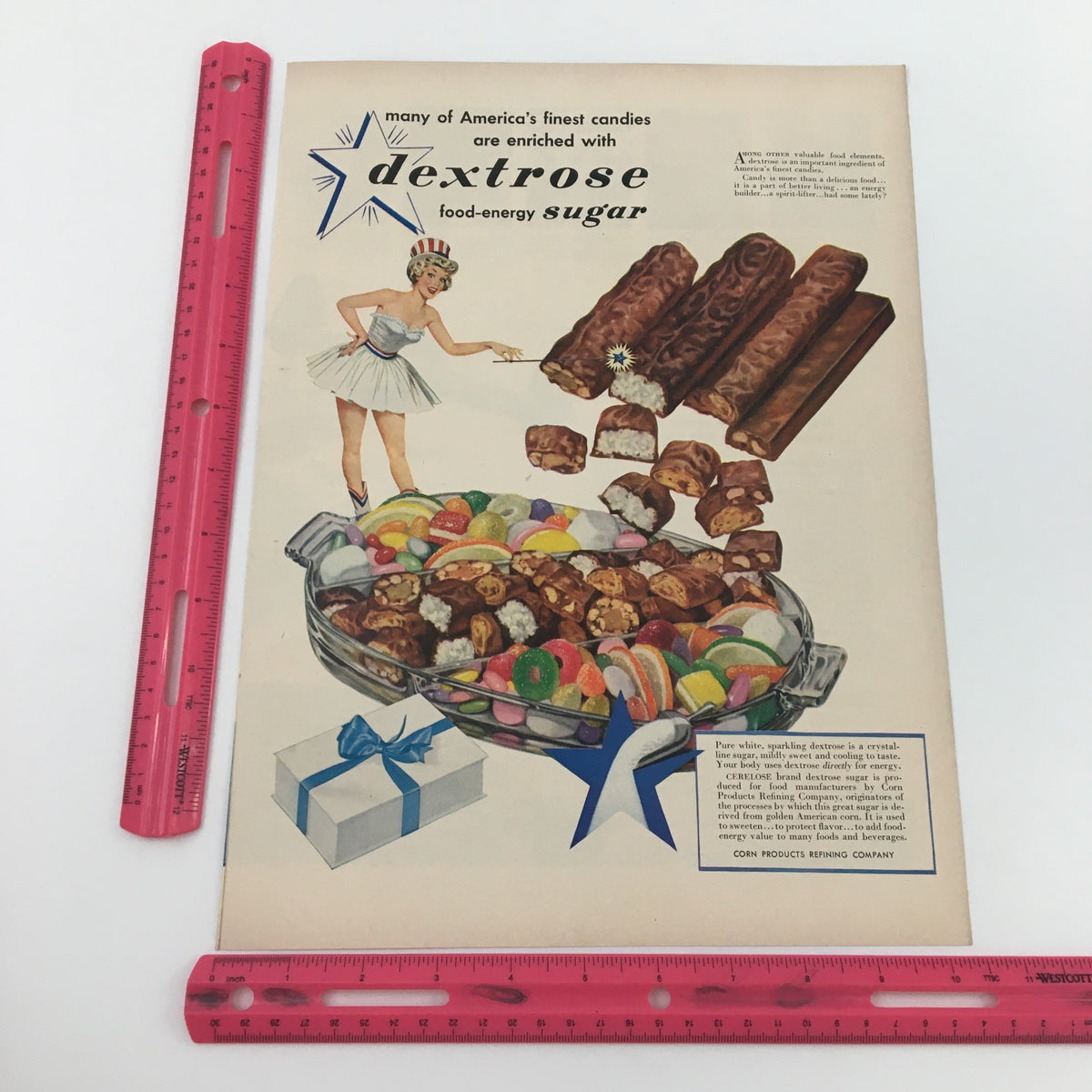 Close-up detail of the 1950 Dextrose Food-Energy Sugar America’s Finest Candies Print Ad, emphasizing vibrant colors and a nostalgic layout with a woman serving candy and showcasing chocolate bars, perfect for collectors of vintage prints.