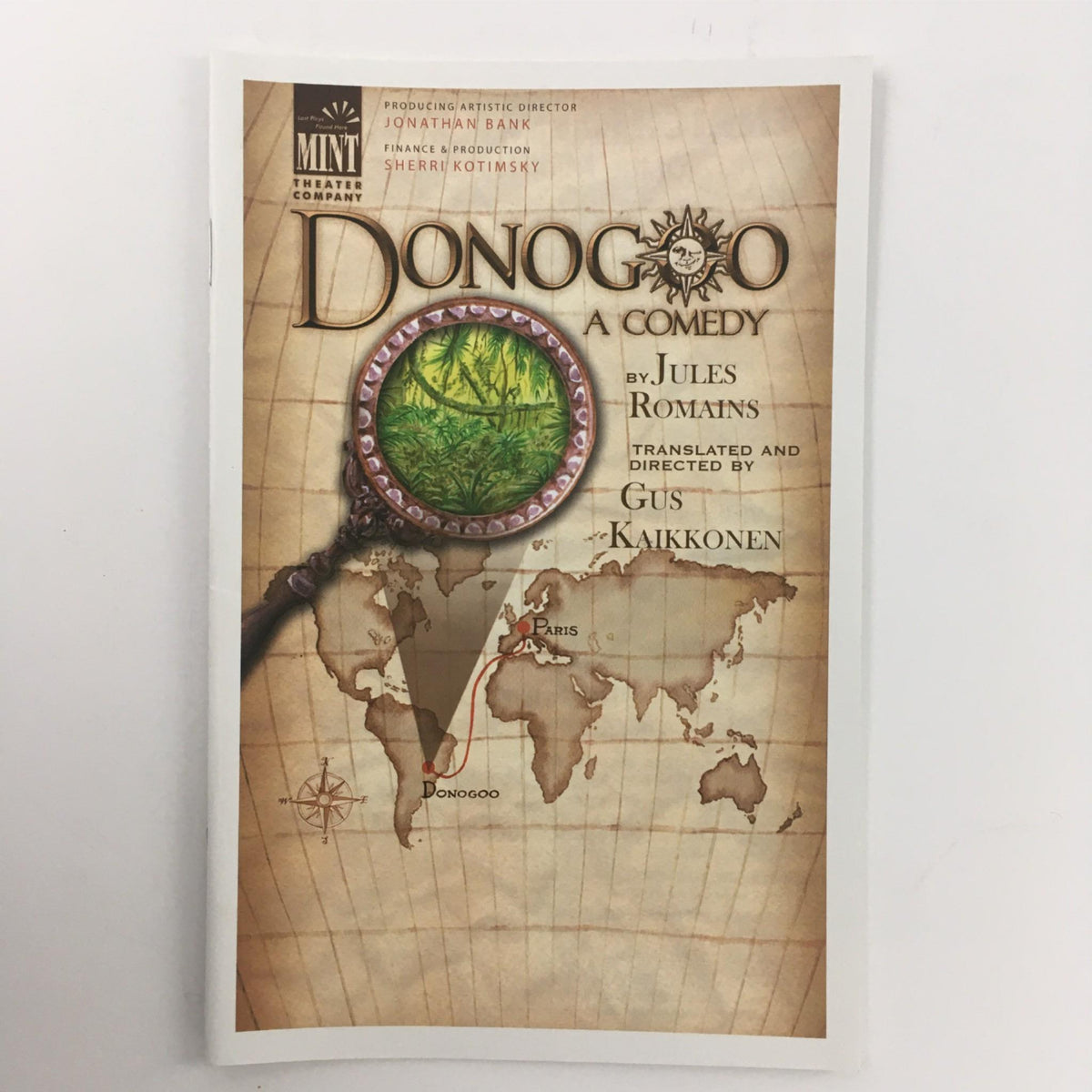 2014 Donogoo A Comedy at Mint Theater Company book cover featuring a magnifying glass and a map with a focus on Donogoo. Written by Jules Roman and directed by Gus Kaikkonen.