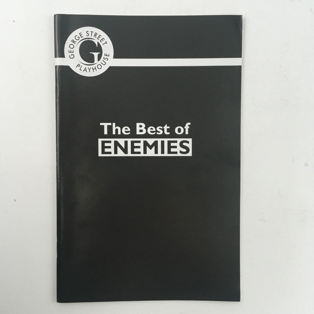Cover of the 2012 The Best of Enemies by Mark St. Germain at George Street Playhouse, featuring a sleek black design with the title prominently displayed in white lettering.